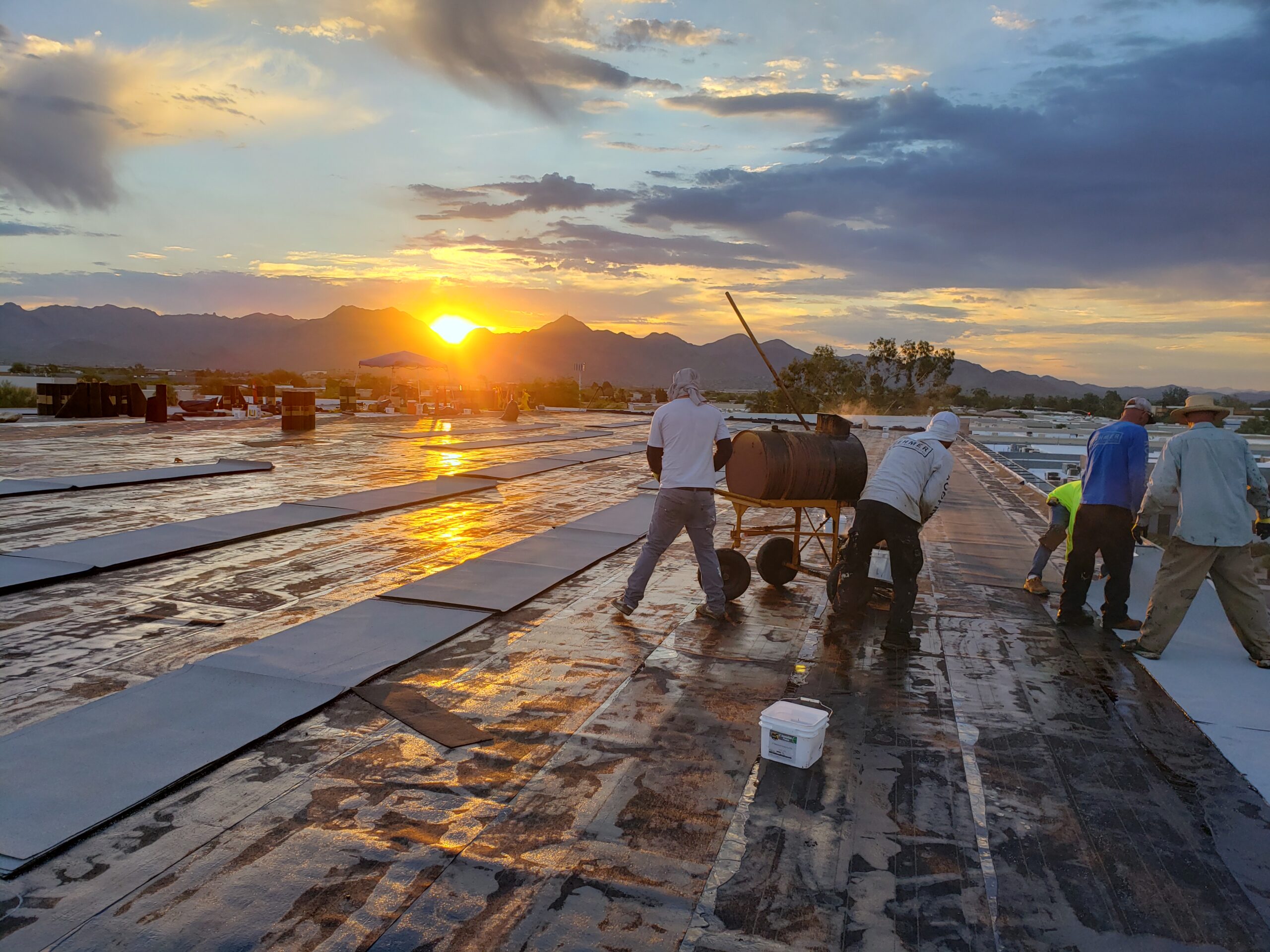 A group of employees working on a new roof in Scottsdale, Arizona at sunset.