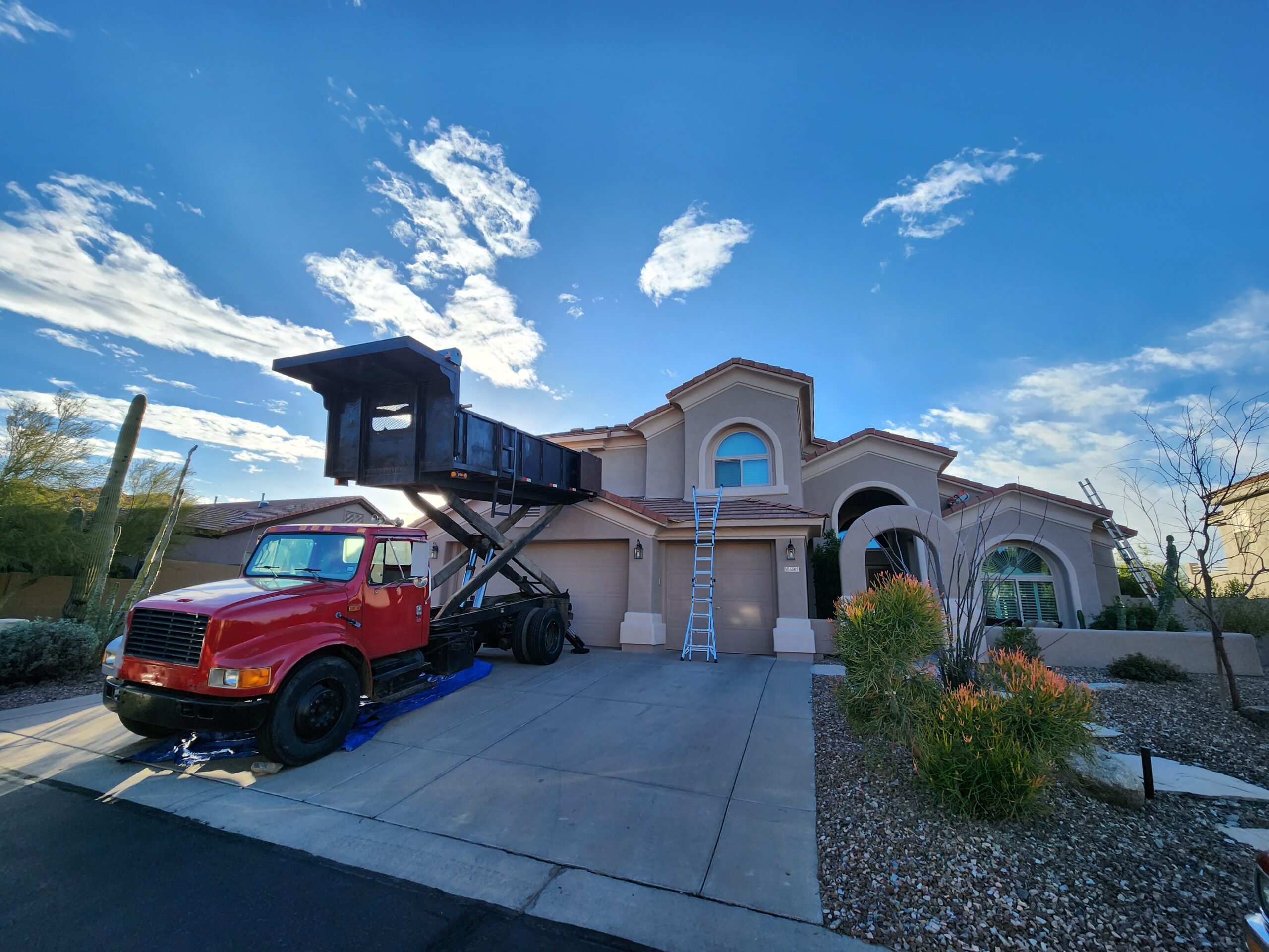 A red dump truck outside home during re roofing in arizona by local contractor Behmer.