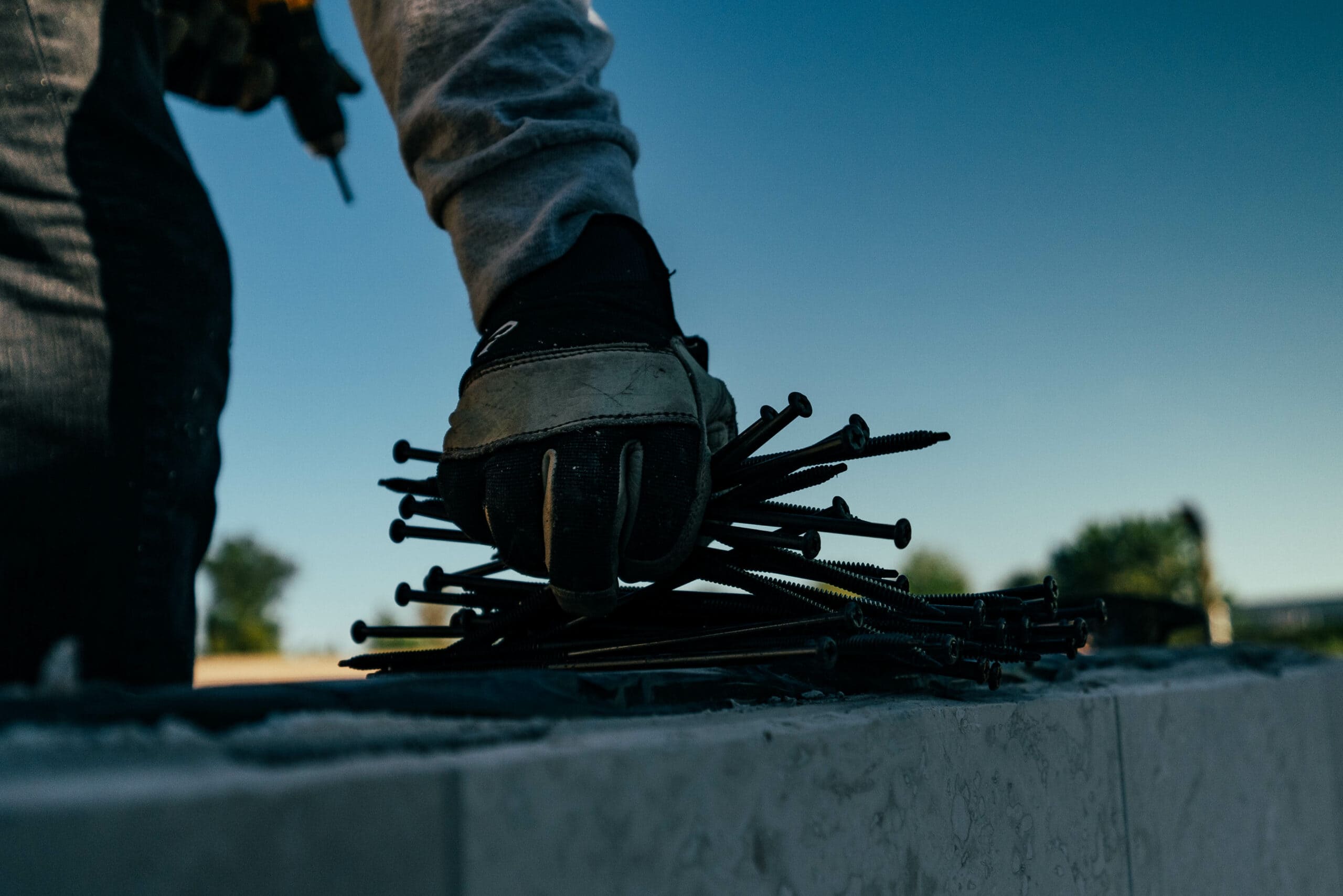 A roofing contractor from North Phoenix is holding nails on a concrete wall.