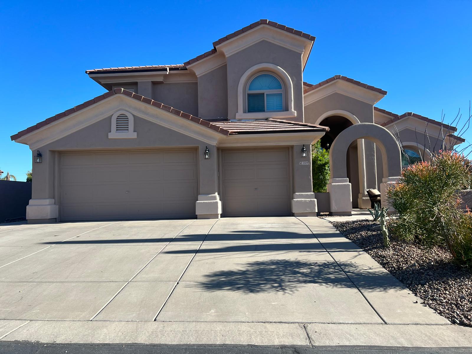 A desert home with a garage, driveway, and tile re-roofing in Cave Creek.