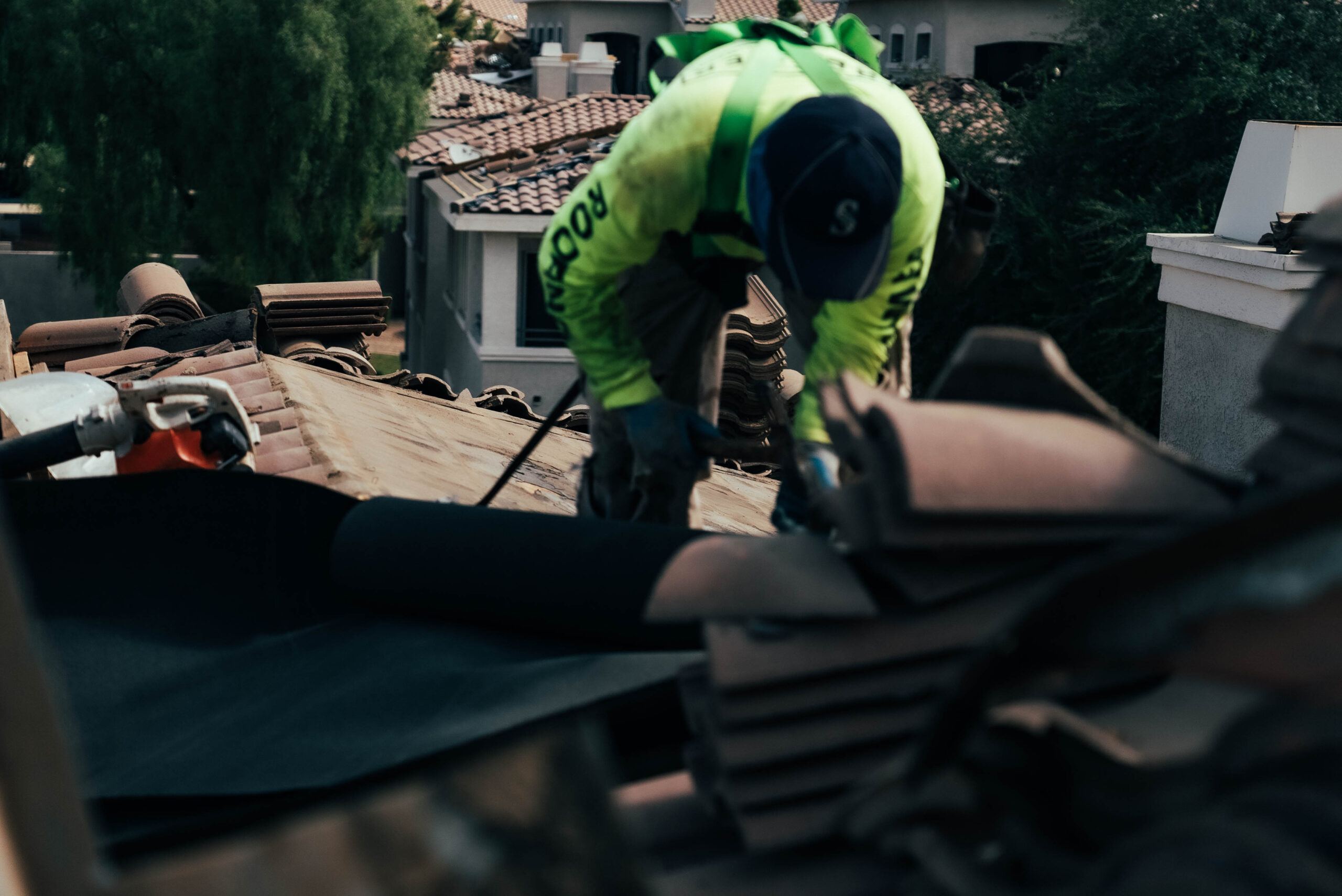 A man is repairing a roof in a residential area.