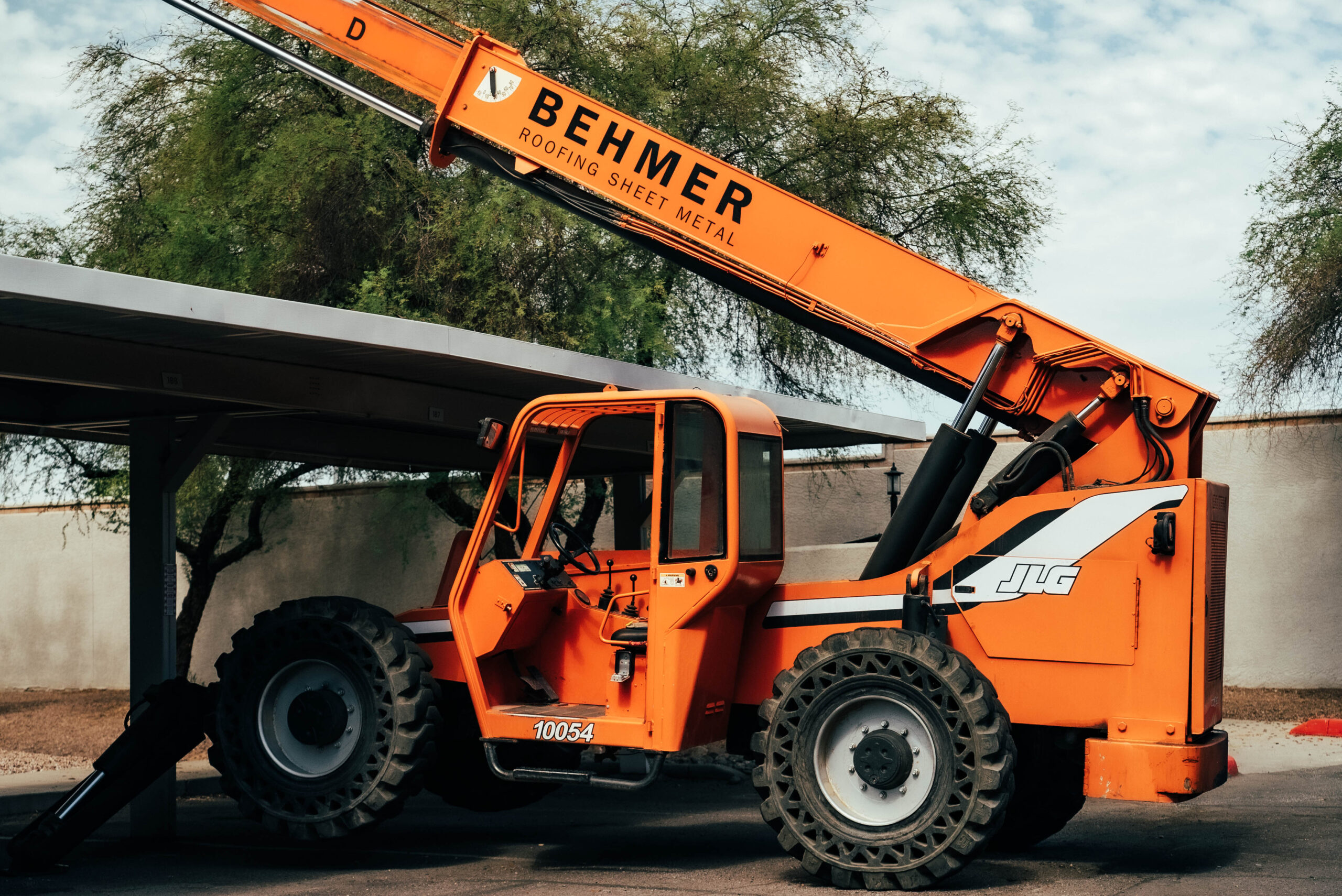 The Biltmore Area roofing contractor has parked a large orange crane in a parking lot.