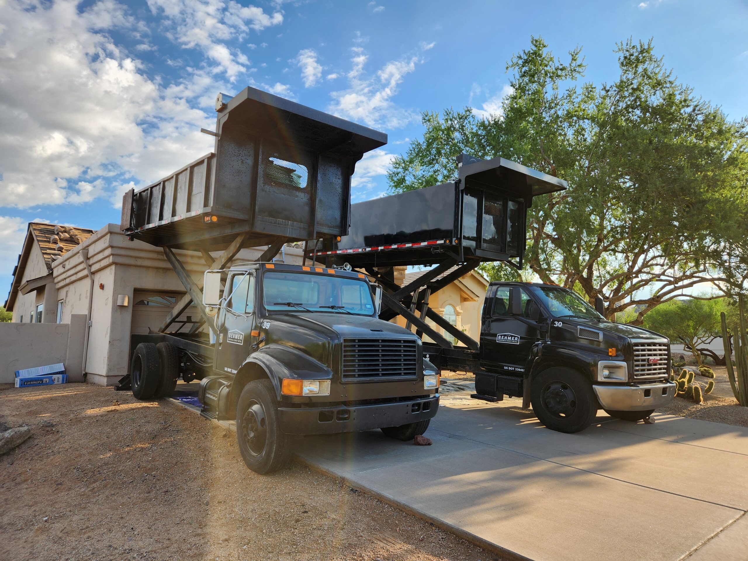 Twin black Behmer trucks parked at a Biltmore area job site, indicating quality service.