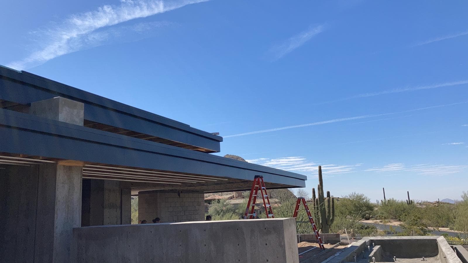A house under construction with a blue sky in the background, featuring metal roofing.