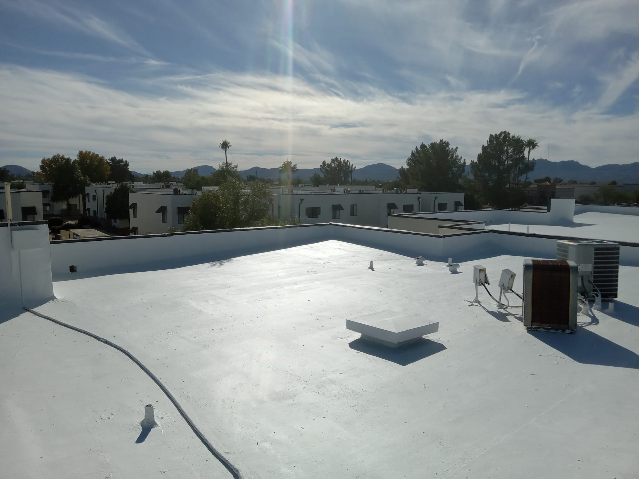 A white roof with a blue sky and mountains in the background, featuring spray foam and coating installation in Scottsdale.
