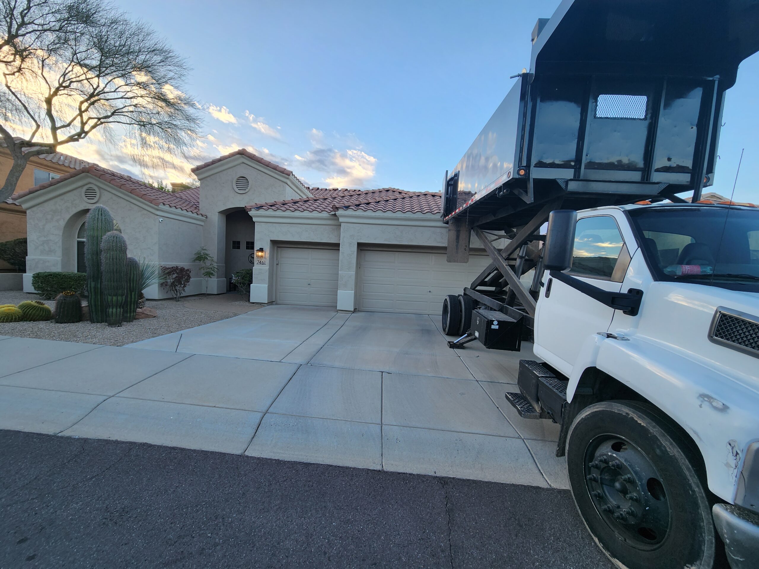 White dumpster truck positioned in front of a Tempe home, signifying ongoing roof work.